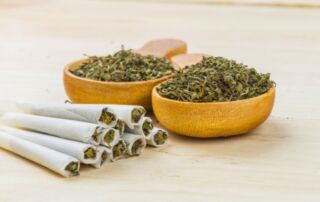 2 bowls of ground flower and a pile of joints
